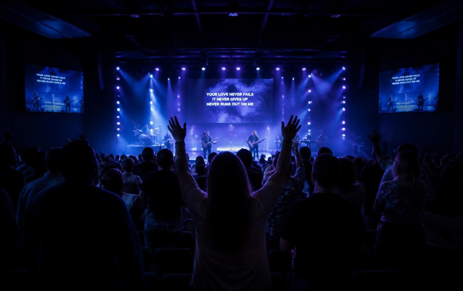 Culto com pessoas adorando em auditório moderno